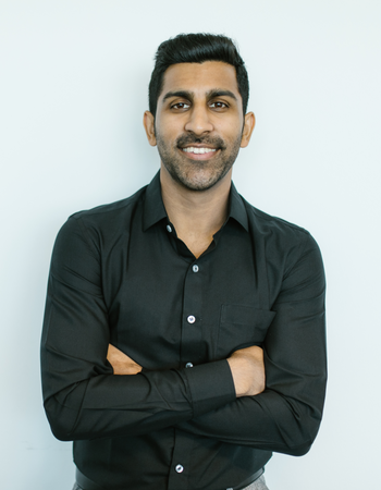 Man wearing a black shirt with arms crossed against a light blue background